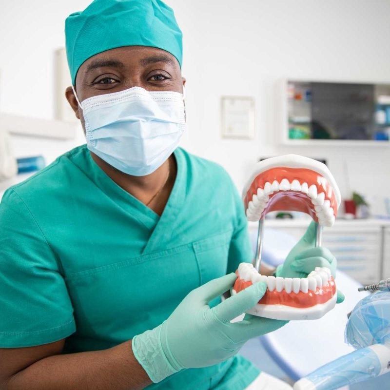an-african-dentist-holding-a-dentition-teeth-model-DPXMZ5M.jpg